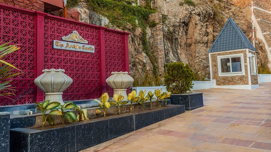 An image of the hotel entrance with the name of the hotel visible and plants placed on a marble platform